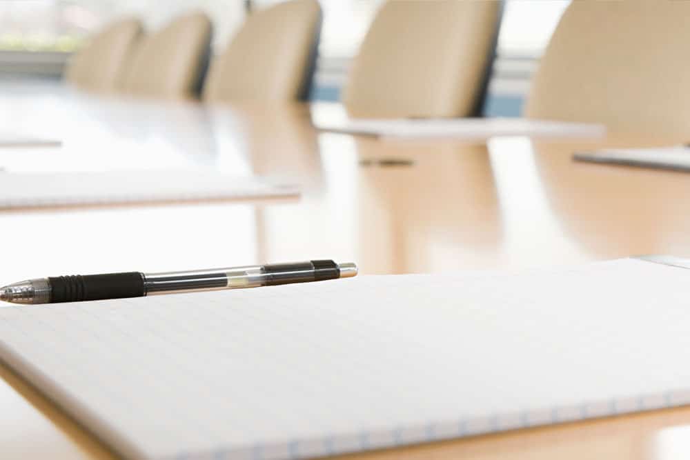 a conference table with many chairs and legal pads on it with pens