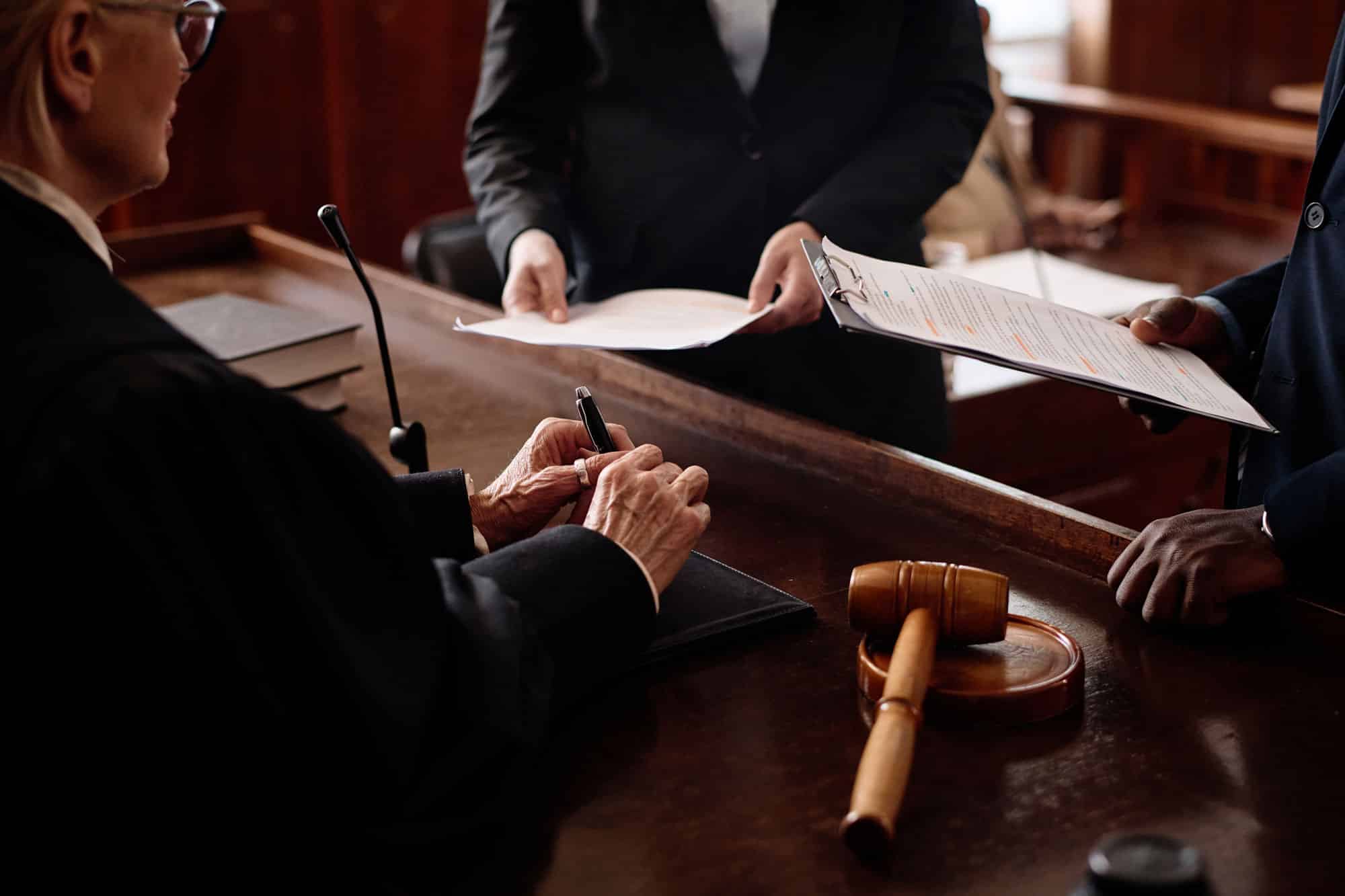close up of a courtroom, at the judge's bench, showing the judge talking to two lawyers